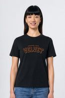 Person wearing a black t-shirt with 'VELVET' text on a plain background