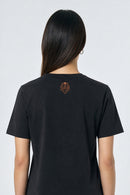 Person wearing a black t-shirt with a logo on the back against a light background