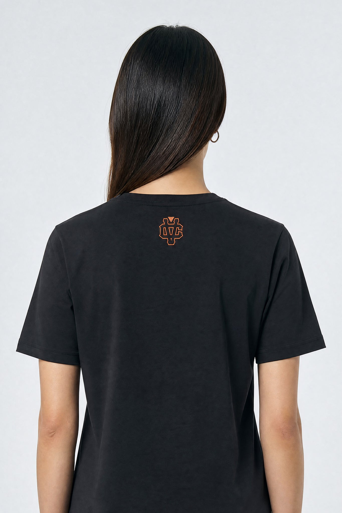 Person wearing a black t-shirt with a logo on the back against a light background