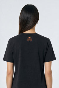 Person wearing a black t-shirt with a logo on the back against a light background
