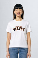 Person wearing a white t-shirt with 'Velvet' text on a plain background
