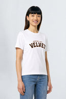 Person wearing a white t-shirt with 'Velvet' text on a plain background