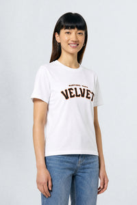 Person wearing a white t-shirt with 'Velvet' text on a plain background