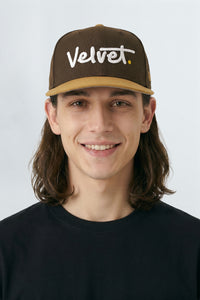 Person wearing a brown cap with 'Velvet' logo on a light gray background