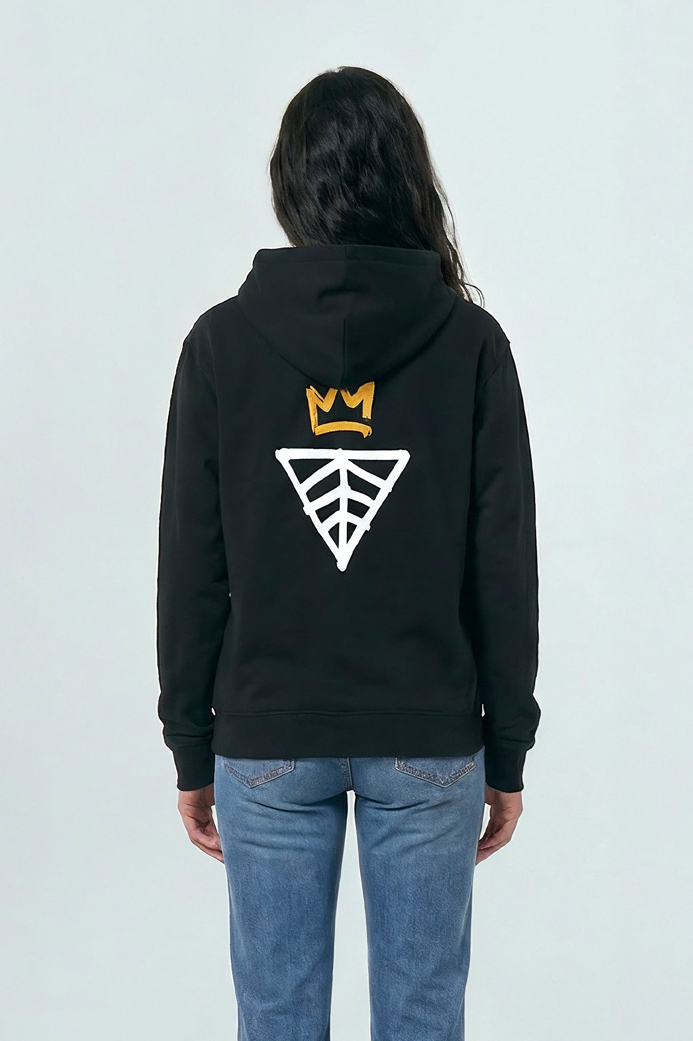 Person wearing a black hoodie with a logo on the back against a light background