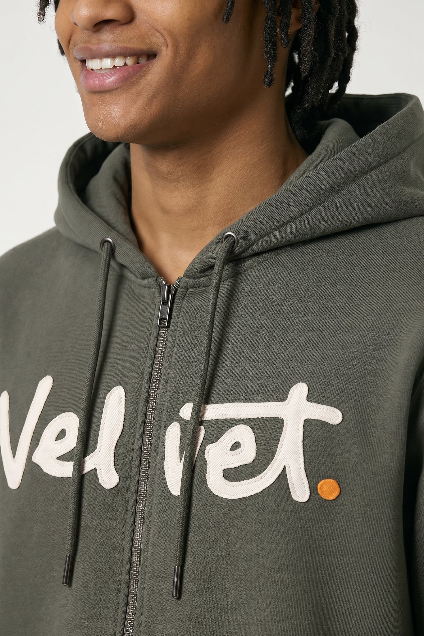 Person wearing a Khaki green hoodie with 'Velvet' logo