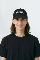 Person wearing a black cap with 'Velvet' text on a white background