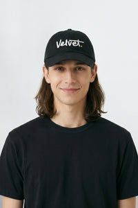 Person wearing a black cap with 'Velvet' text on a white background