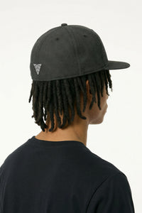 Person wearing a black cap with a logo on a background