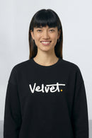 Person wearing a black sweatshirt with 'Velvet' text on a light background