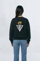 Person wearing a black sweatshirt with a logo on the back against a light background