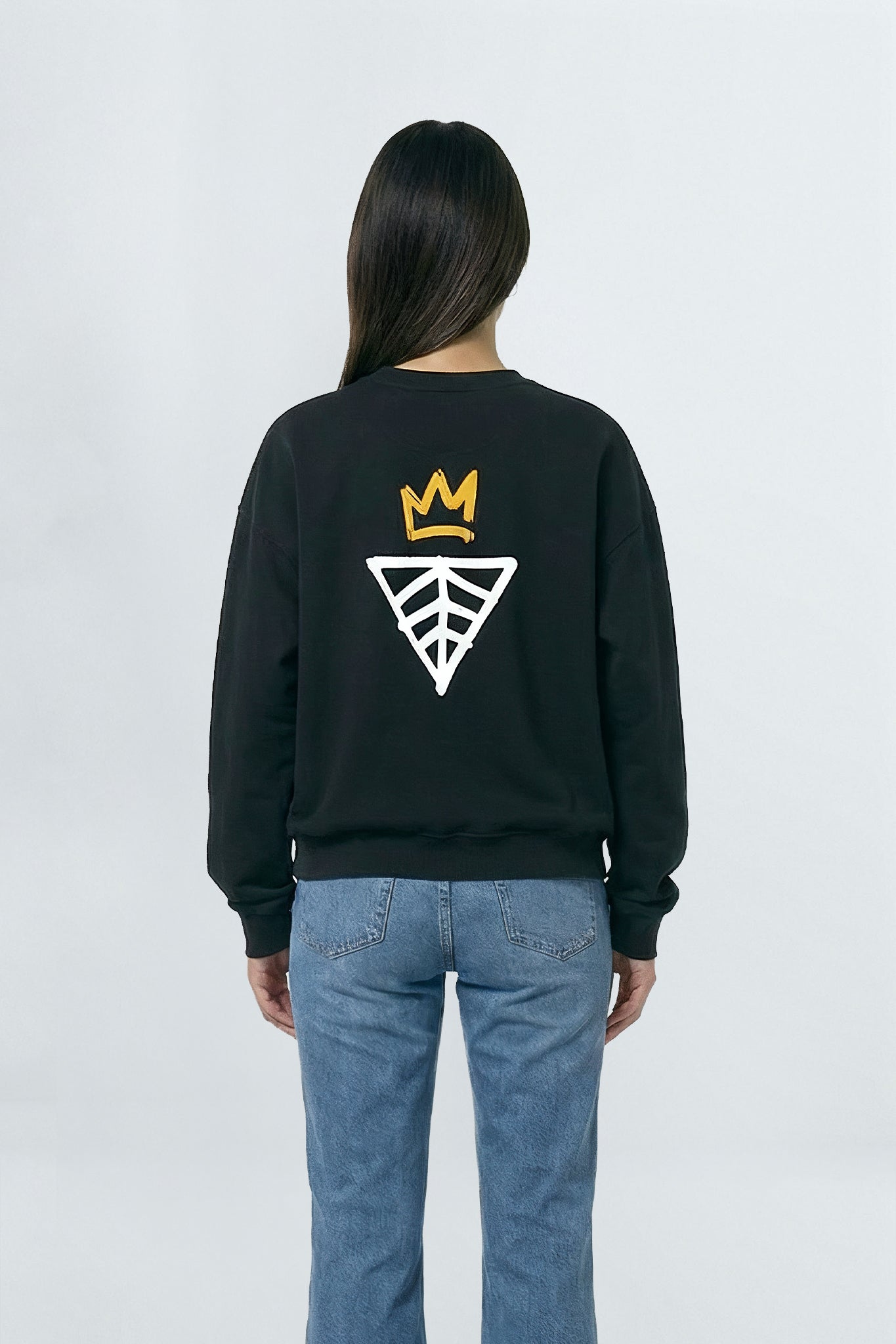 Person wearing a black sweatshirt with a logo on the back against a light background