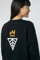 Person wearing a black sweatshirt with a logo on the back against a light background