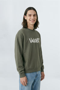 Person wearing a Khaki green sweatshirt with 'Velvet' text on a light background
