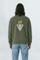 Person wearing a khaki green sweatshirt with a logo on the back against a light background
