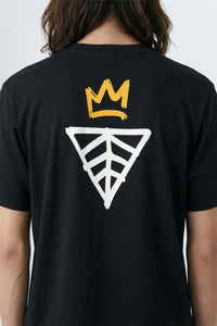 Black t-shirt with a yellow crown and geometric design on the back, worn by a person.