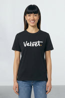 Person wearing a black t-shirt with 'Velvet' logo on a plain background