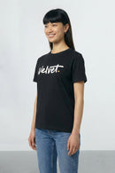 Person wearing a black t-shirt with 'Velvet' text on a plain background