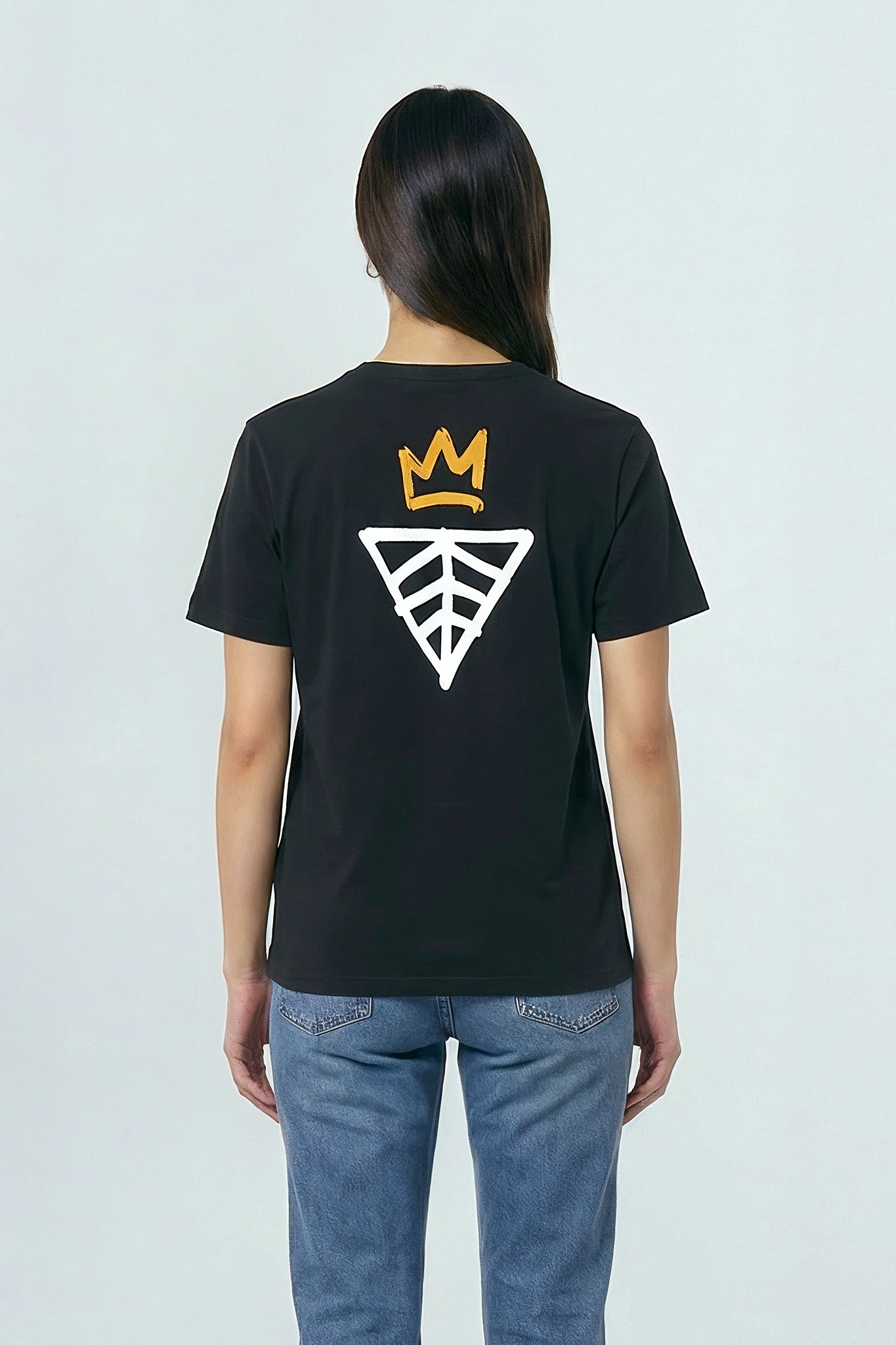 Person wearing a black t-shirt with a logo on the back against a light background