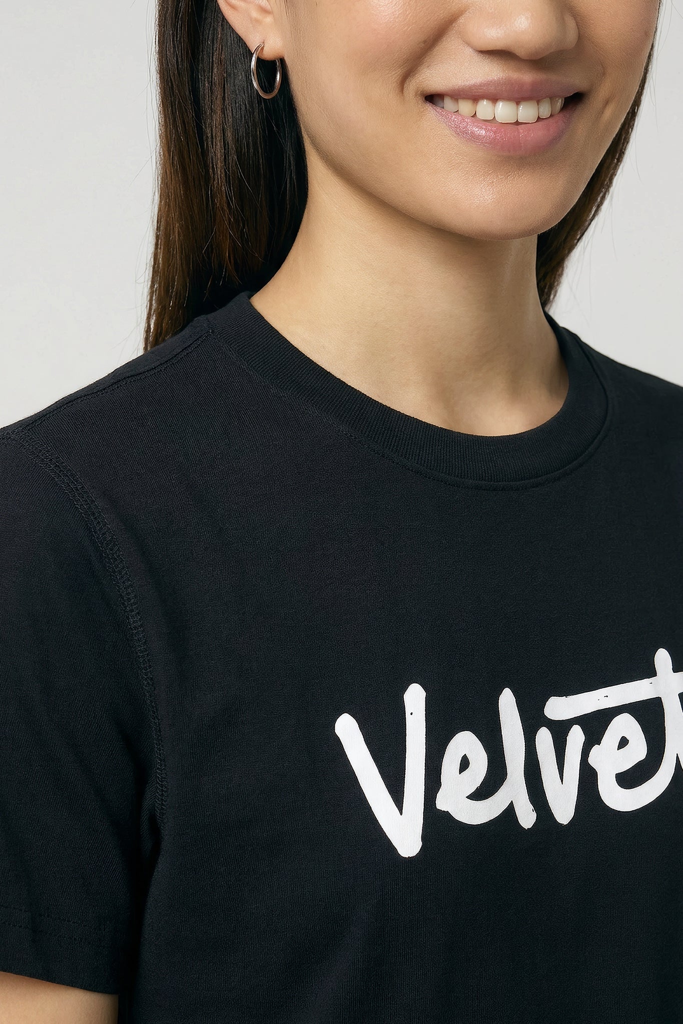 Person wearing a black t-shirt with 'Velvet' printed on it against a background