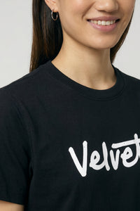 Person wearing a black t-shirt with 'Velvet' printed on it against a background