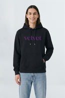 Person wearing a black hoodie with 'velvet' text on a light background