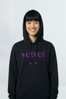 Person wearing a black hoodie with 'velvet' text on a light background