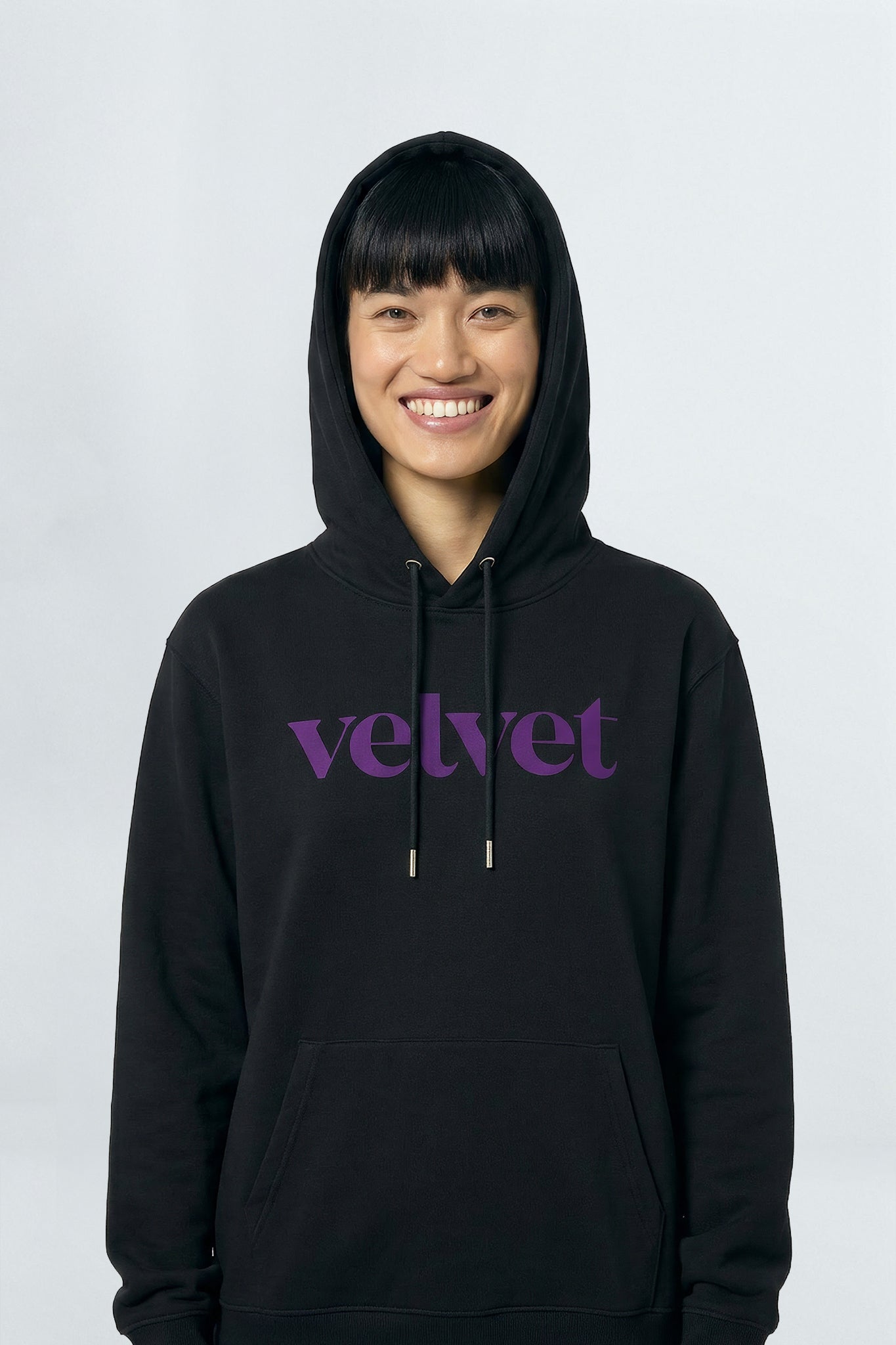 Person wearing a black hoodie with 'velvet' text on a light background
