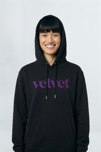 Person wearing a black hoodie with 'velvet' text on a light background
