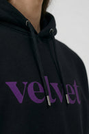 Black hoodie with 'velvet' text  on a neutral background
