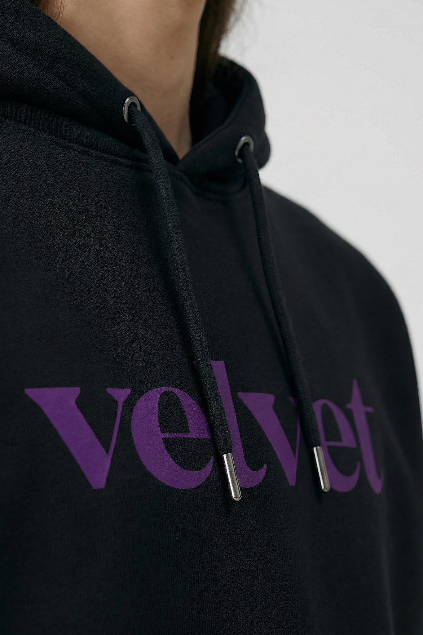 Black hoodie with 'velvet' text  on a neutral background