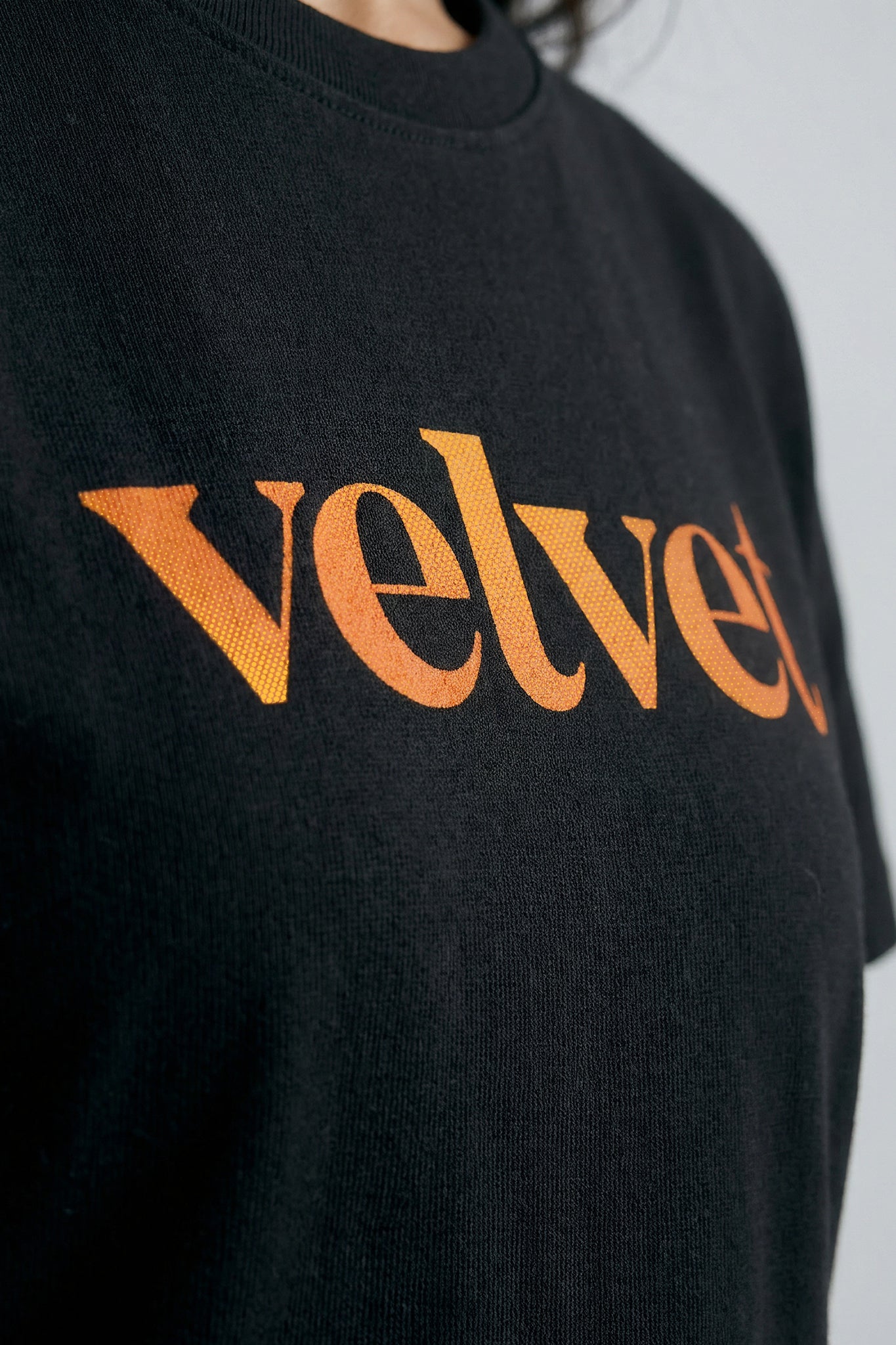 Black t-shirt with Orange  'velvet' text on a plain background