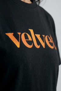 Black t-shirt with Orange  'velvet' text on a plain background