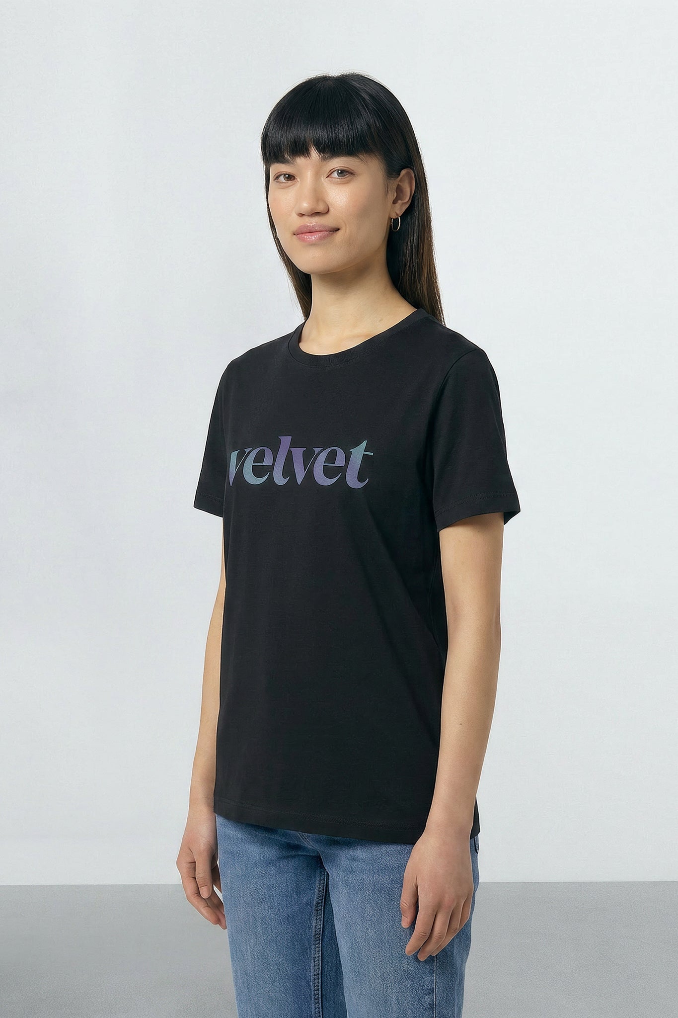 Person wearing a black t-shirt with 'velvet' text on a plain background