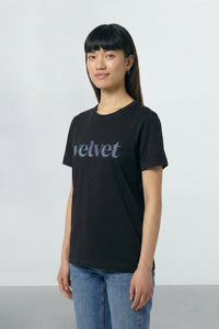 Person wearing a black t-shirt with 'velvet' text on a plain background