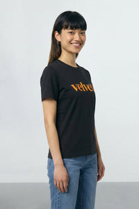 Person wearing a black t-shirt with 'velvet' text on a plain background