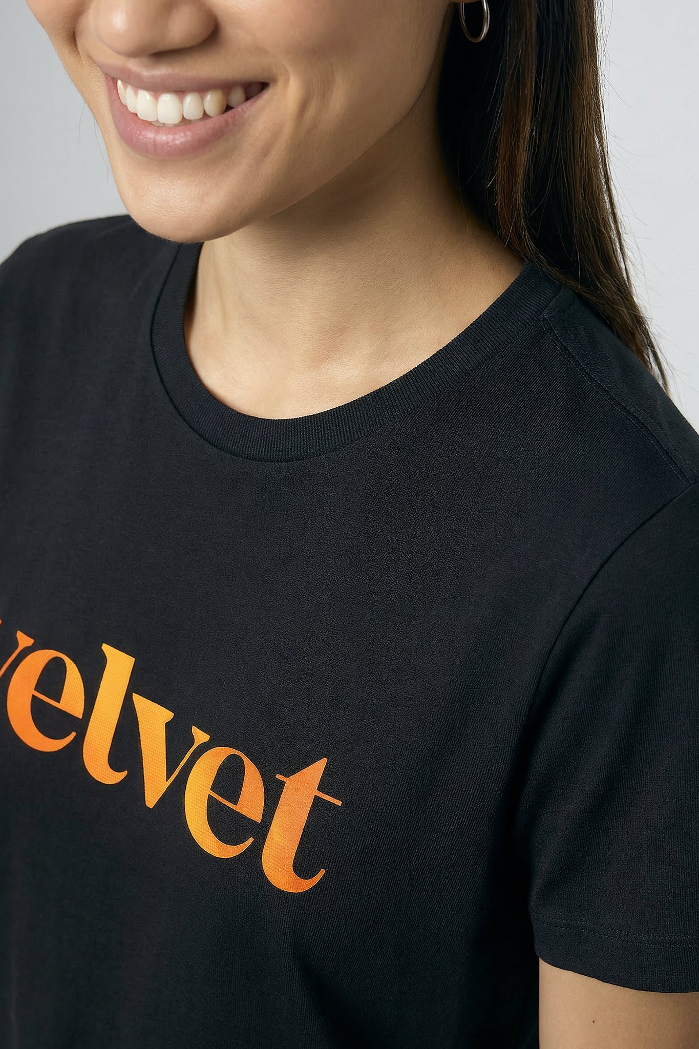 Person wearing a black t-shirt with 'velvet' printed in orange.