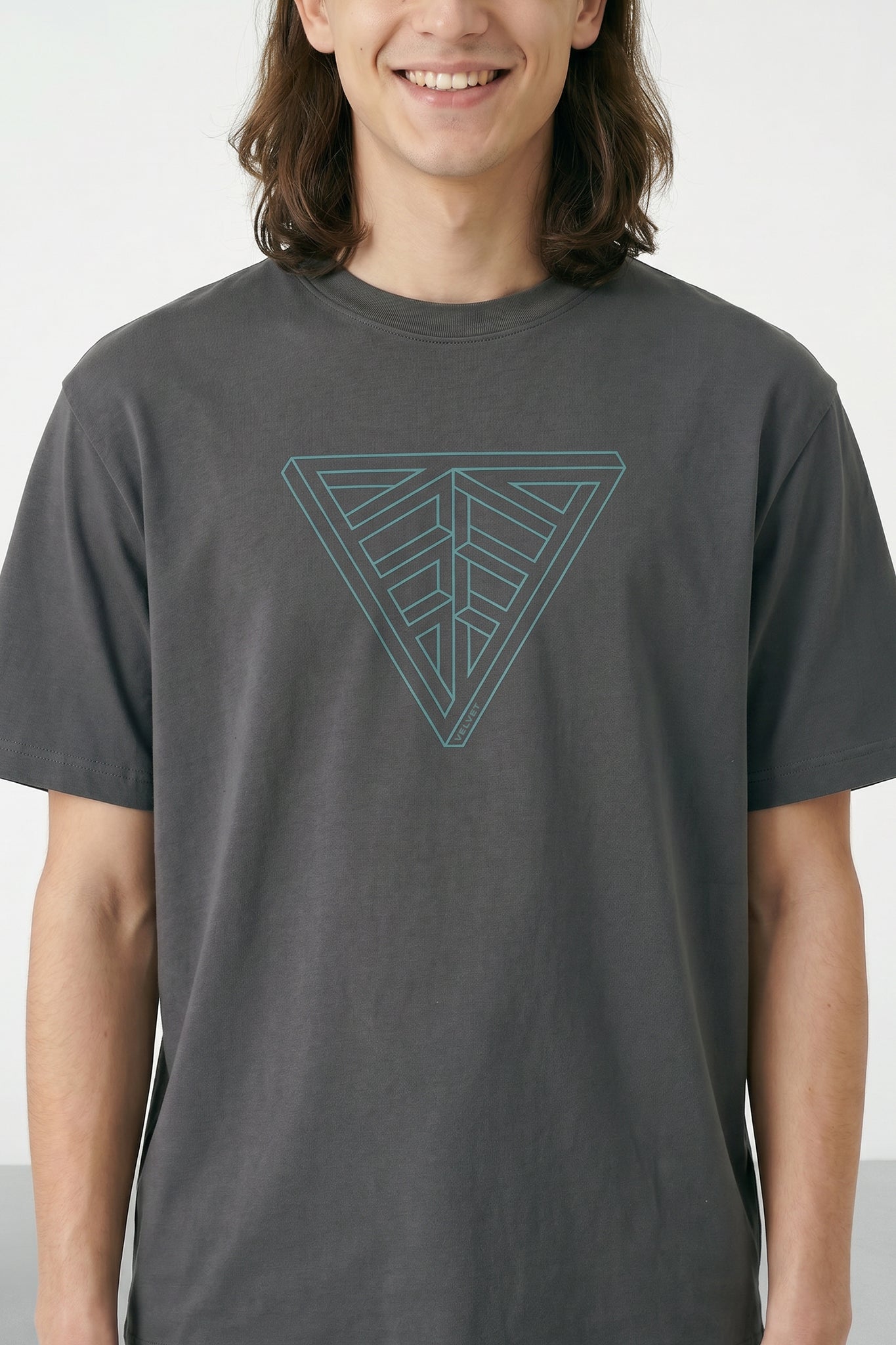 Person wearing a gray t-shirt with a geometric triangle design on a plain background