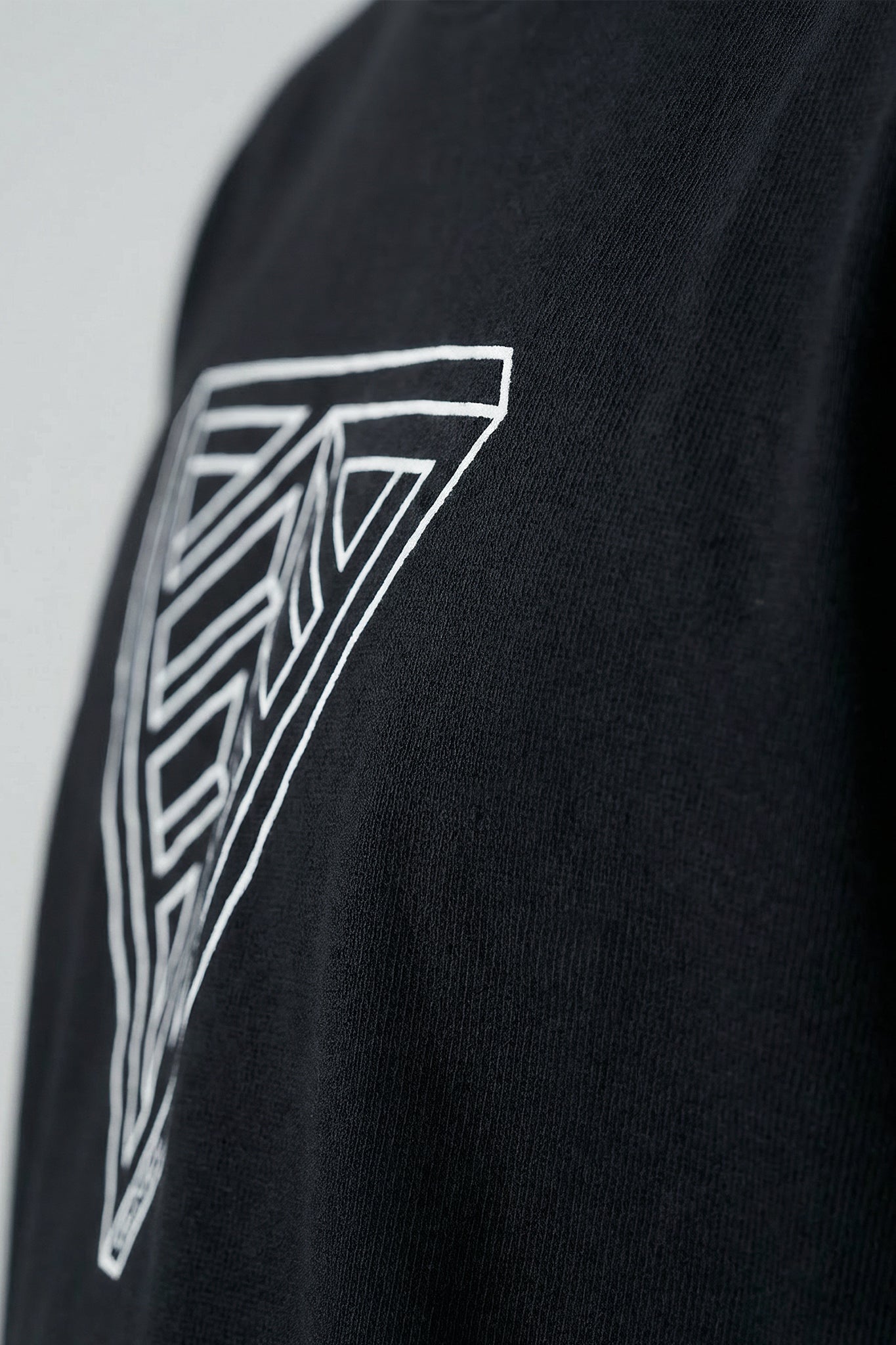 Black t-shirt with a geometric triangle design on a plain background