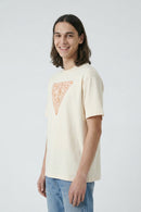 Person wearing a beige t-shirt with a geometric design on a plain background
