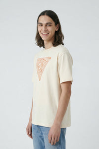 Person wearing a beige t-shirt with a geometric design on a plain background