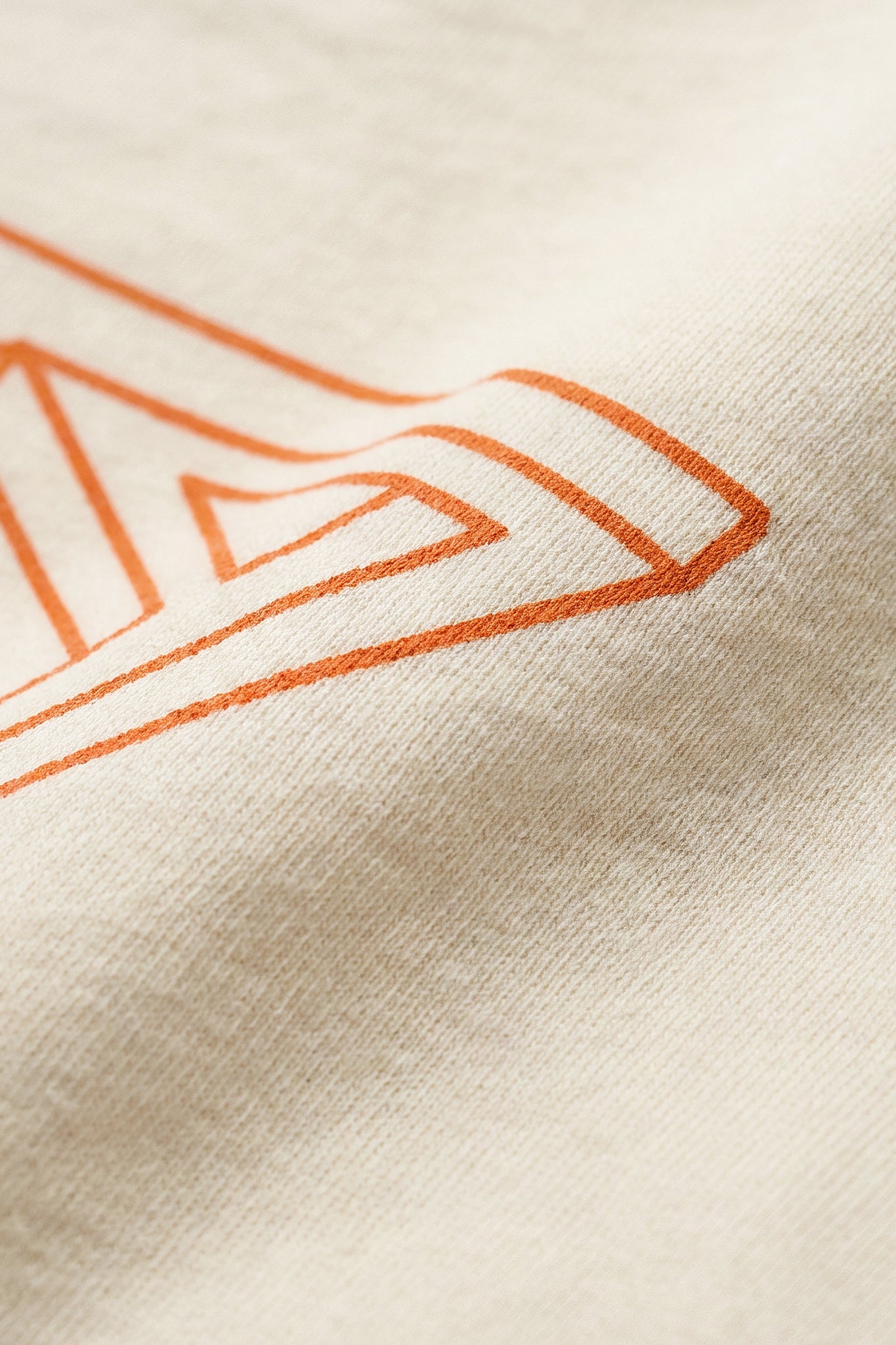 Close-up of a beige fabric with an orange geometric pattern