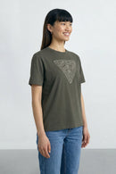 Woman wearing a Khaki green  t-shirt with a geometric design on a plain background
