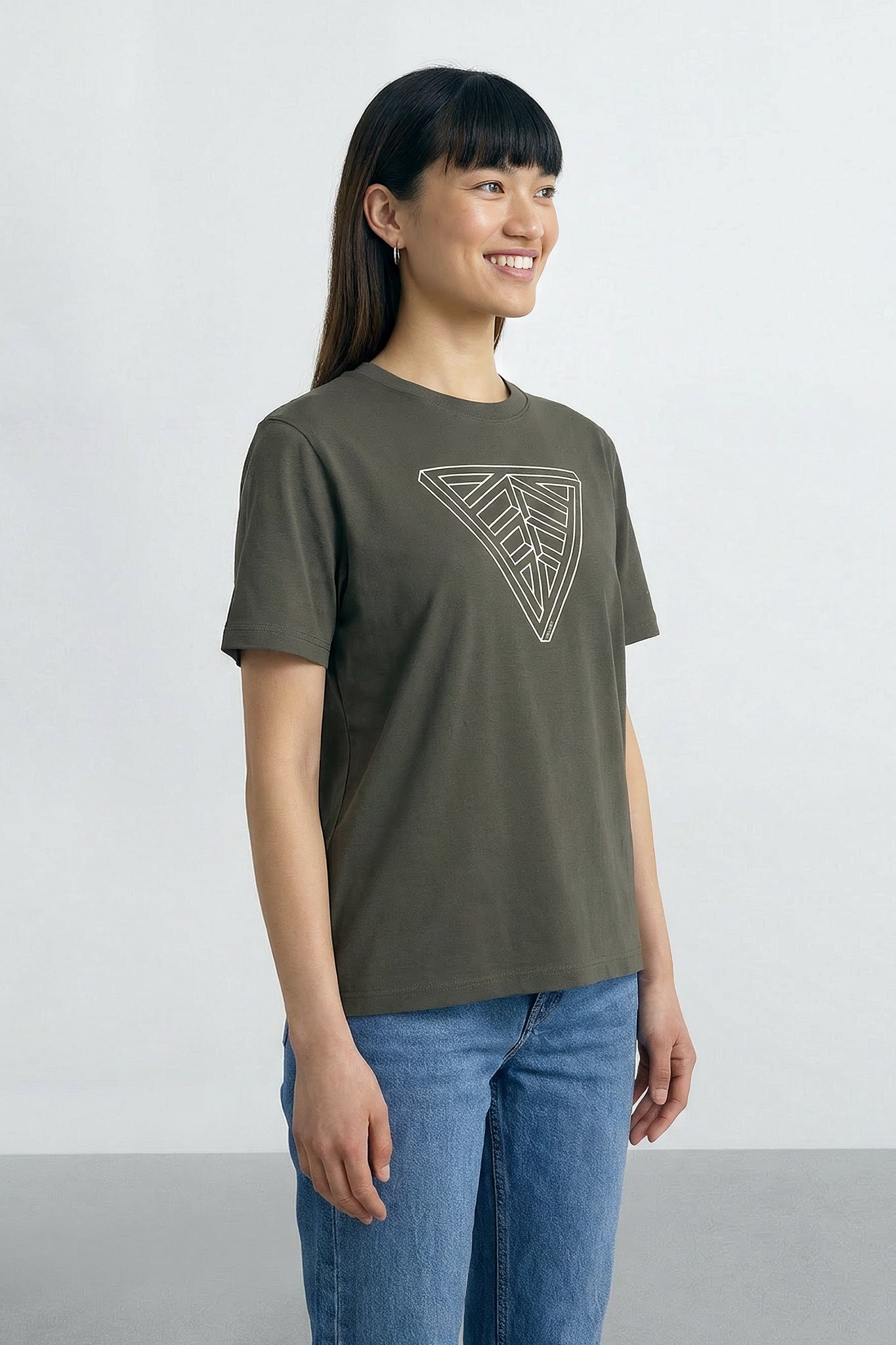 Woman wearing a Khaki green  t-shirt with a geometric design on a plain background
