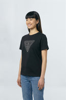 Person wearing a black t-shirt with a geometric design on a plain background