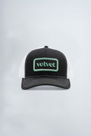 Black and white cap with 'velvet' logo on a light background