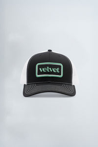 Black and white cap with 'velvet' logo on a light background