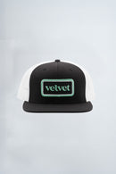 Black and white cap with 'velvet' logo on a light background