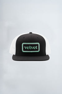 Black and white cap with 'velvet' logo on a light background