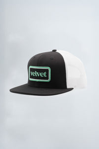 Black and white cap with 'velvet' logo on a light background